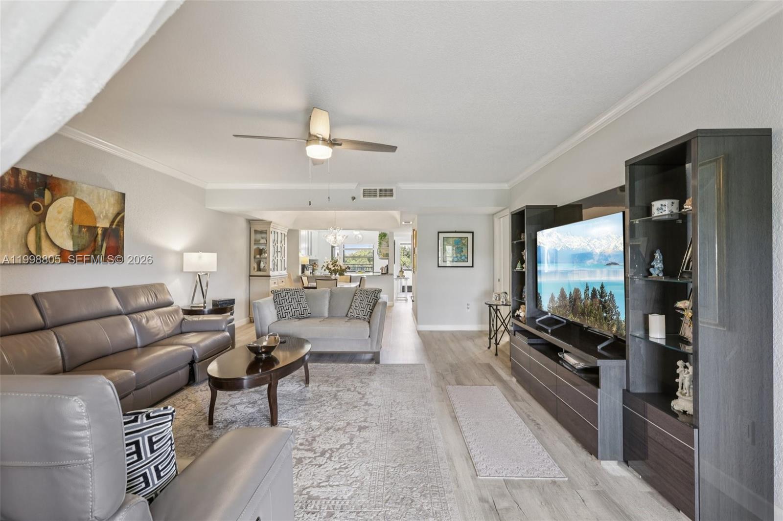 A living room features grey leather furniture, a large media console, and light wood flooring — 9170 SW 14th St # 4508, Boca Raton FL 33428, BOCA RATON, FL
