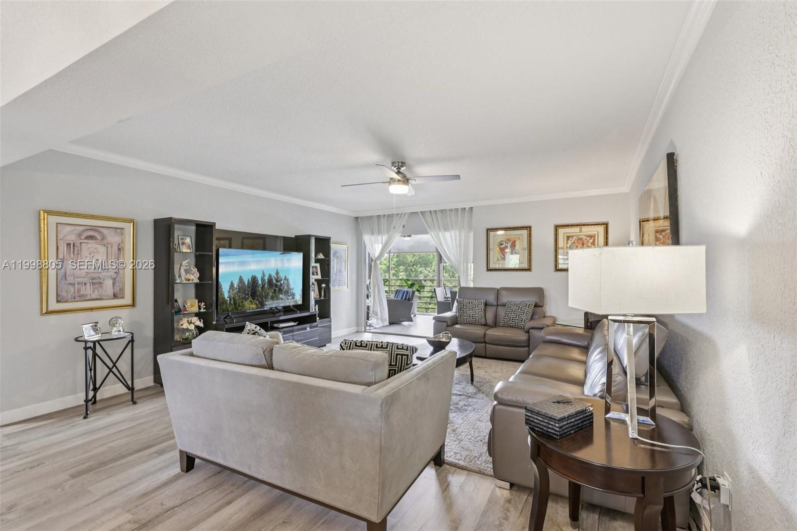 A living room features light wood floors, gray sofas, a television console, and a balcony — 9170 SW 14th St # 4508, Boca Raton FL 33428, BOCA RATON, FL