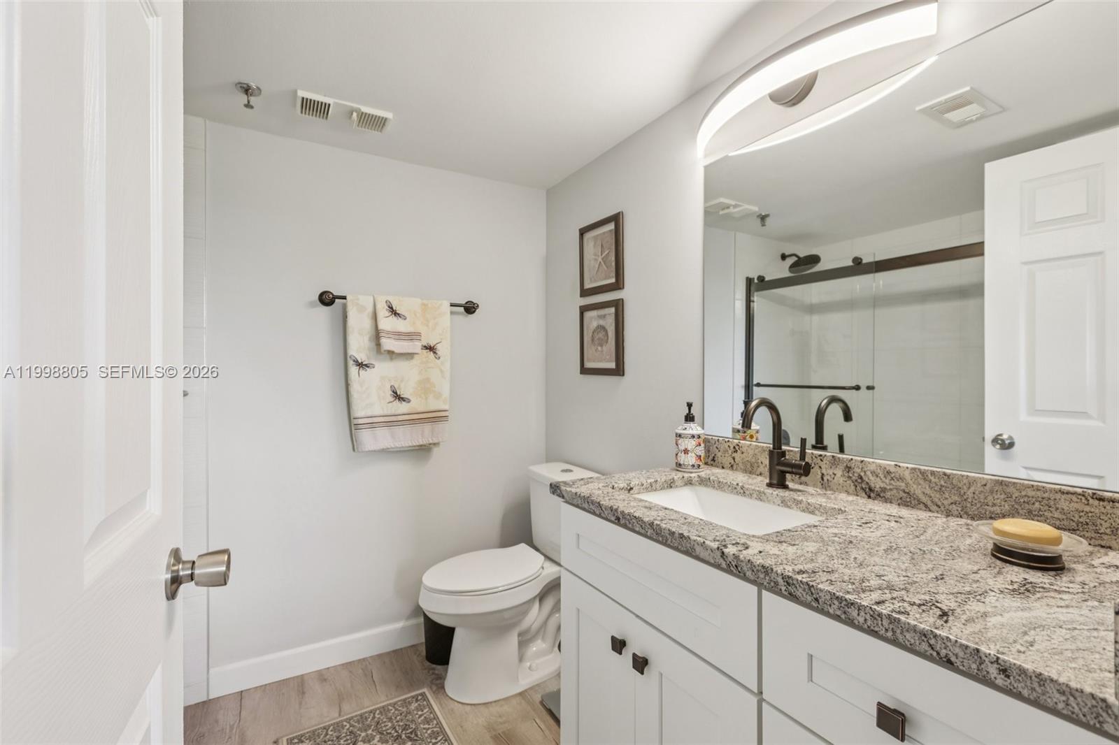 A bathroom features a white vanity with granite countertops, a toilet, and a glass shower — 9170 SW 14th St # 4508, Boca Raton FL 33428, BOCA RATON, FL