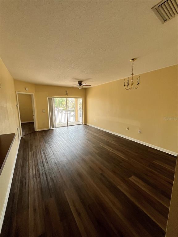 An empty living room features wood-look flooring, a ceiling fan, and a sliding glass door — 6456 CYPRESSDALE DRIVE UNIT 202, RIVERVIEW, FL