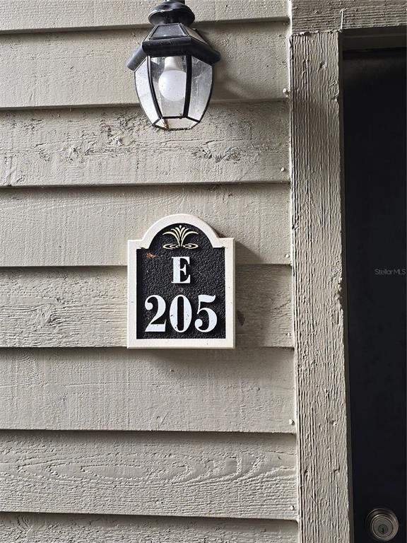A close-up view of a building exterior showing a light fixture and unit number E 205 — 2500 WINDING CREEK BOULEVARD UNIT E205, CLEARWATER, FL