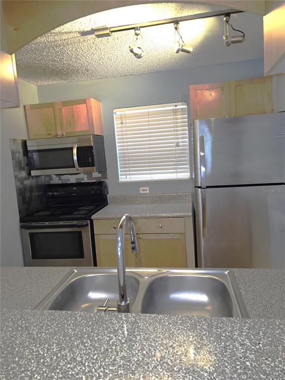 A kitchen features stainless steel appliances, speckled countertops, and a double-basin sink — 2500 WINDING CREEK BOULEVARD UNIT E205, CLEARWATER, FL