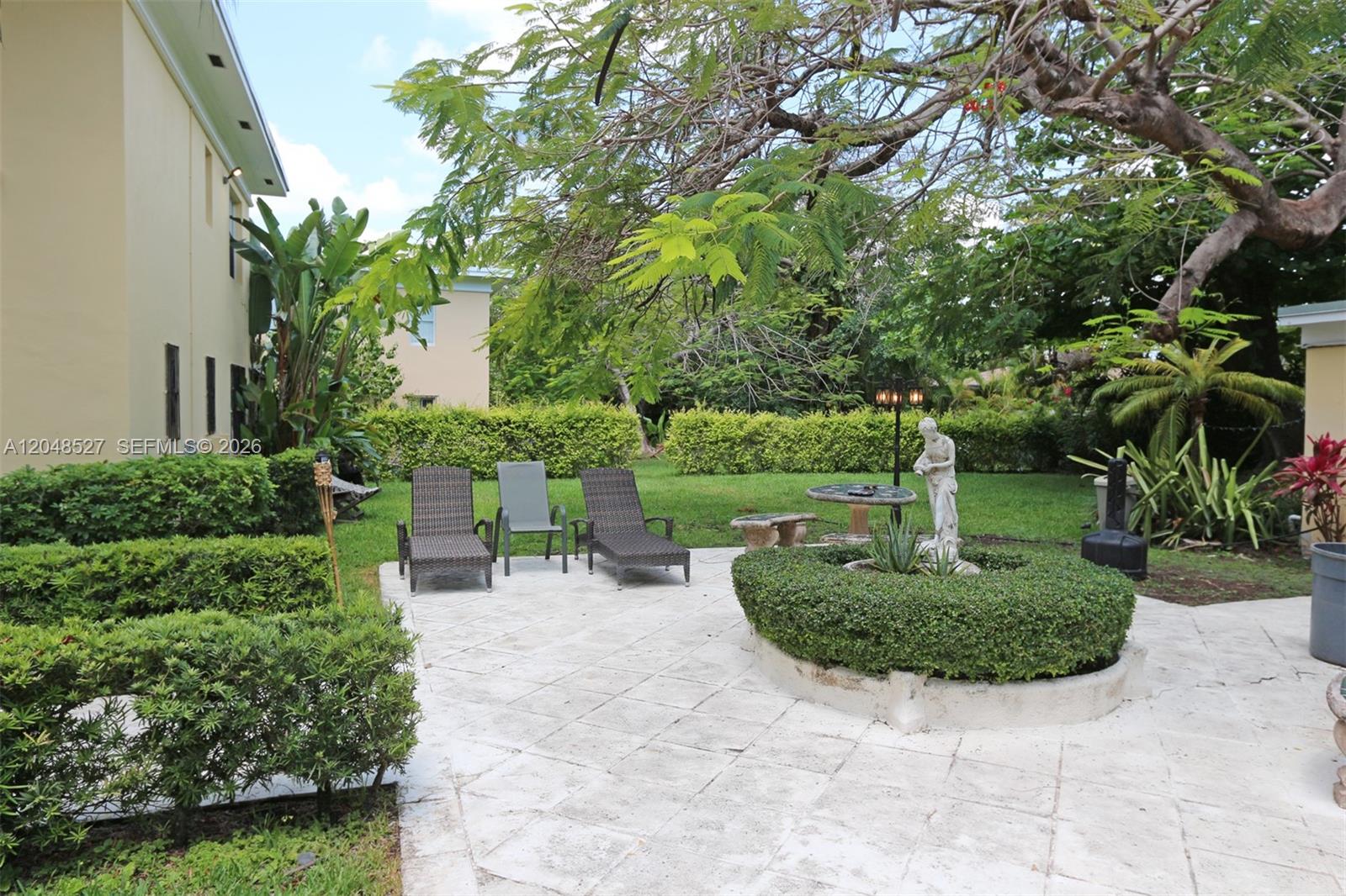 A paved patio features lounge chairs, a circular hedge, and a statue in a garden — 3395 Franklin Ave # D, Miami FL 33133, MIAMI, FL