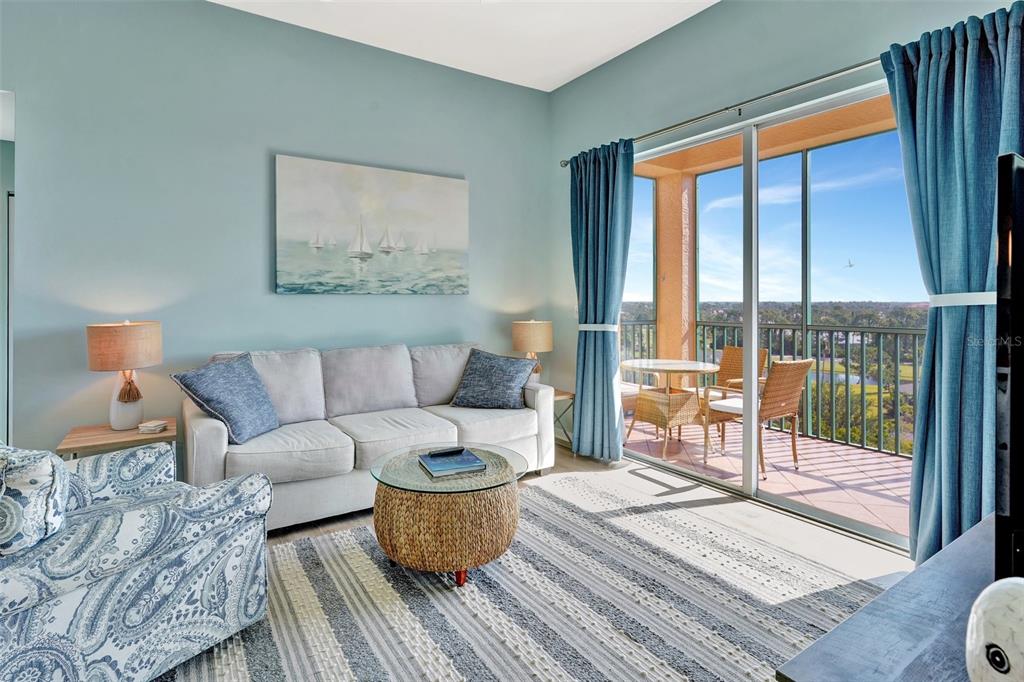 A living room features a sofa, patterned armchair, round coffee table, and a balcony with views — 2090 MATECUMBE KEY ROAD UNIT 1708, PUNTA GORDA, FL