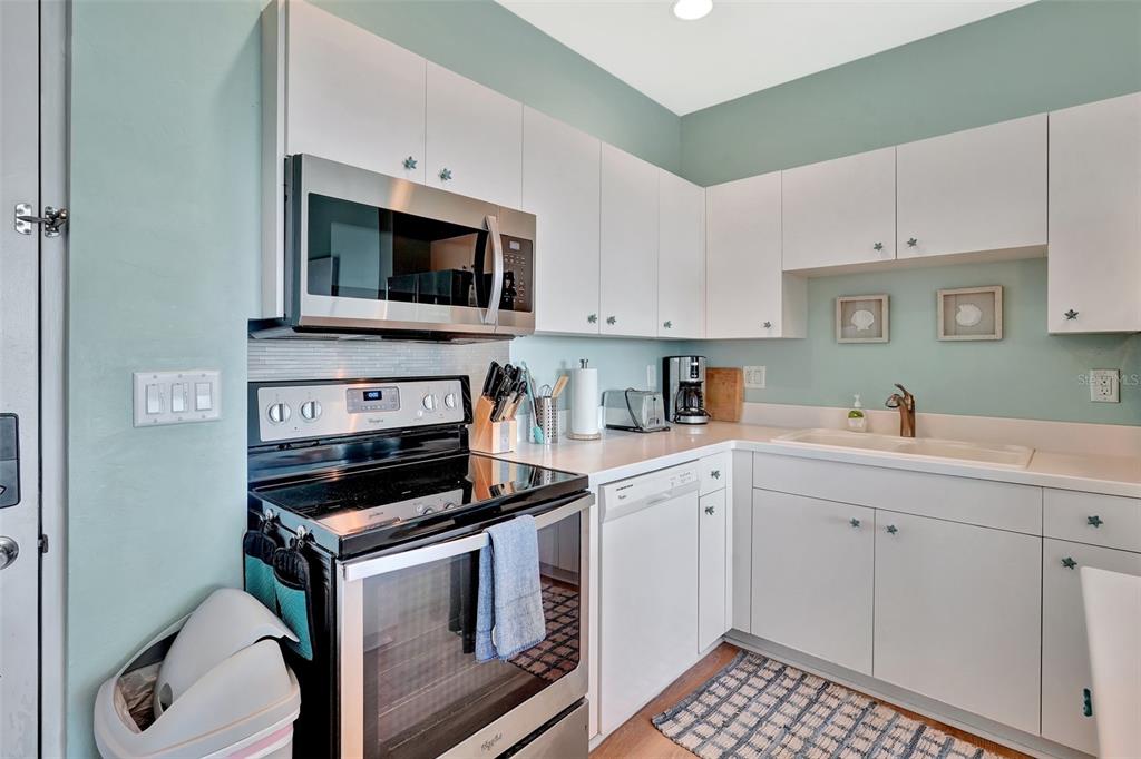 A kitchen features white cabinets, stainless steel appliances, a light blue wall, and a sink — 2090 MATECUMBE KEY ROAD UNIT 1708, PUNTA GORDA, FL