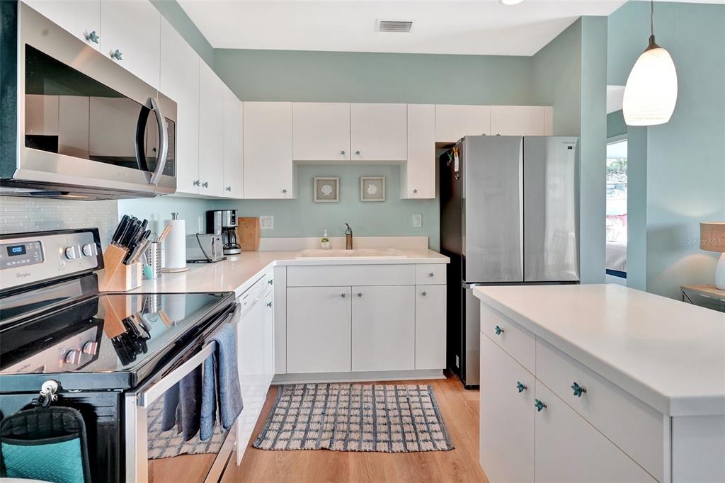 A kitchen features white cabinets, stainless steel appliances, light countertops, and light blue walls — 2090 MATECUMBE KEY ROAD UNIT 1708, PUNTA GORDA, FL