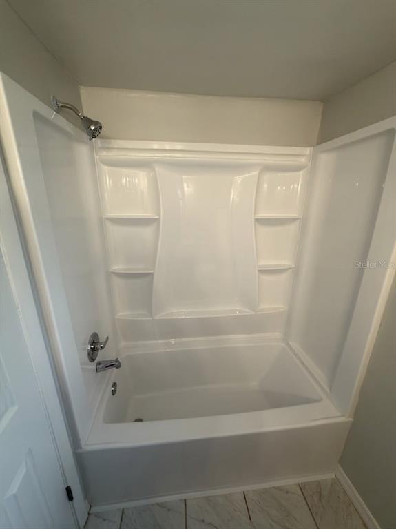 A white bathtub and shower surround with built-in shelving in a tiled bathroom — 827 SKY LAKE CIRCLE UNIT A, ORLANDO, FL