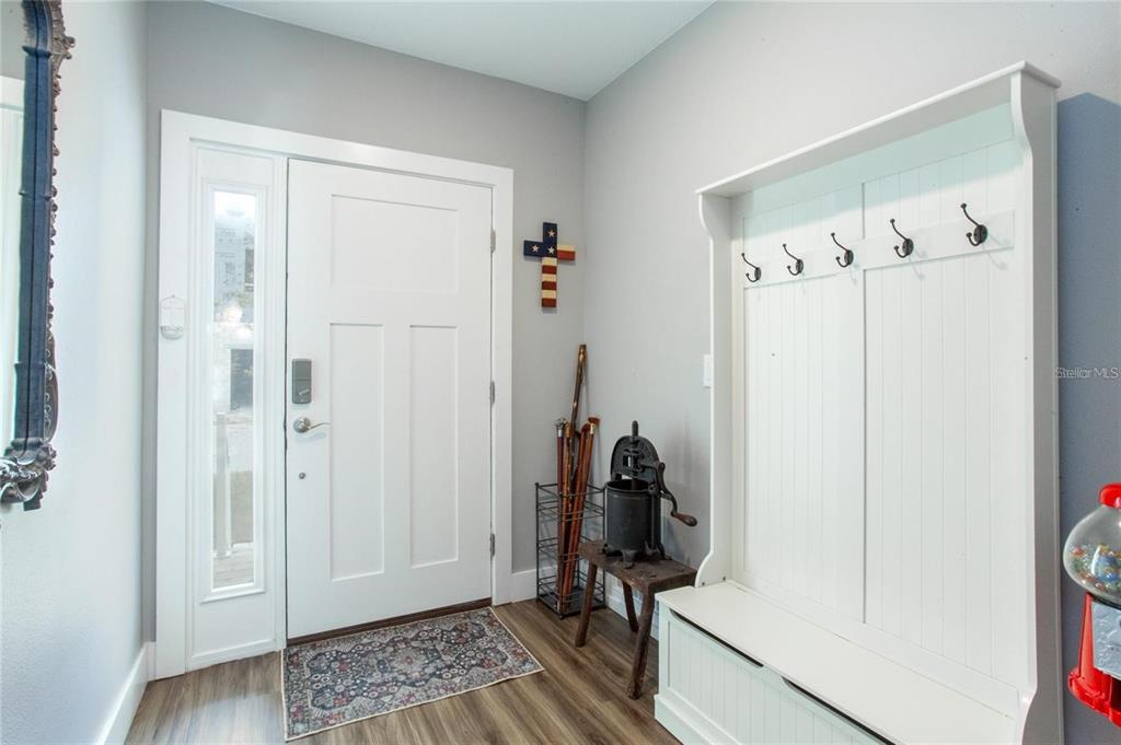 An entryway features a white front door, a coat rack bench, and wood-look flooring — 1273 SAVONA DRIVE NE, ST PETERSBURG, FL