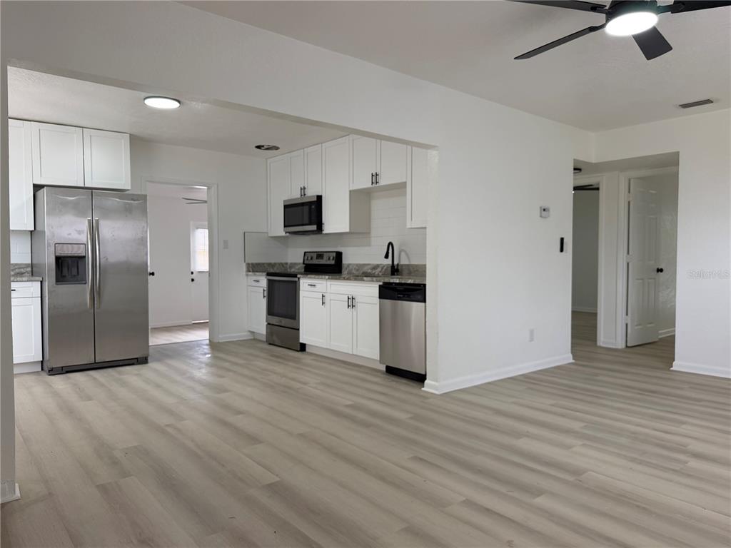A kitchen with white cabinets, stainless steel appliances, and light wood-look flooring — 10909 N 14TH STREET, TAMPA, FL