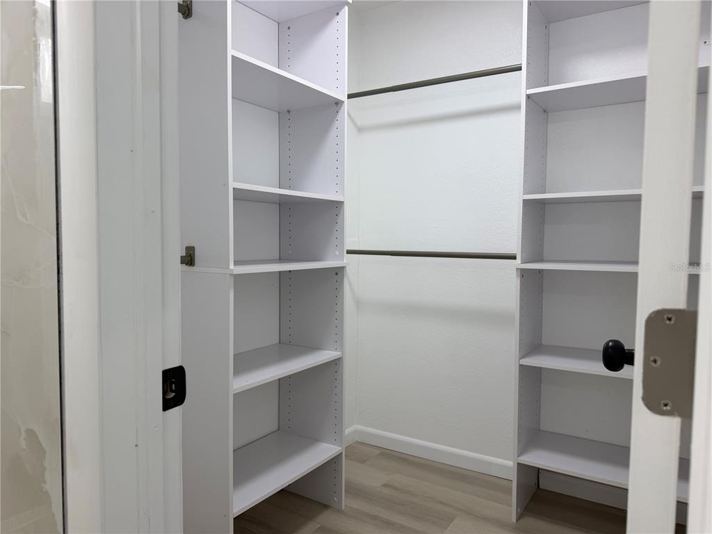 A walk-in closet features white shelving units on both sides and two horizontal hanging rods — 10909 N 14TH STREET, TAMPA, FL
