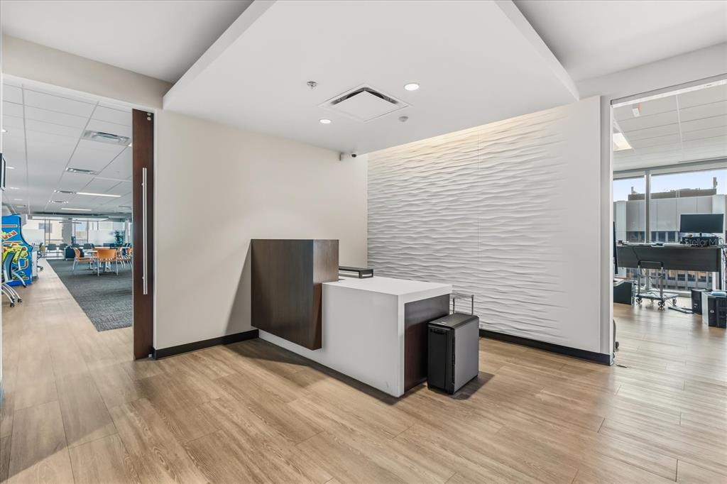 A modern office reception area features a white and wood desk against a textured wall — 189 S ORANGE AVENUE UNIT 1900-1970, ORLANDO, FL