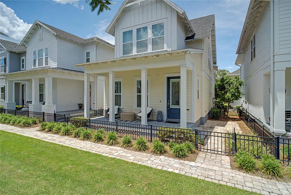 A two-story house with light yellow siding, a front porch, and a black metal fence — 914 TROWMAN ALLEY, WINTER GARDEN, FL