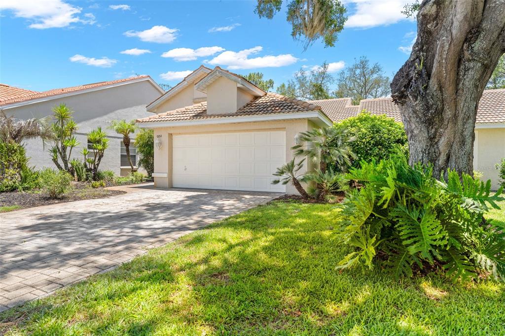 A beige house with a two-car garage and a paved driveway under a blue sky — 9354 MISSISSIPPI RUN, WEEKI WACHEE, FL