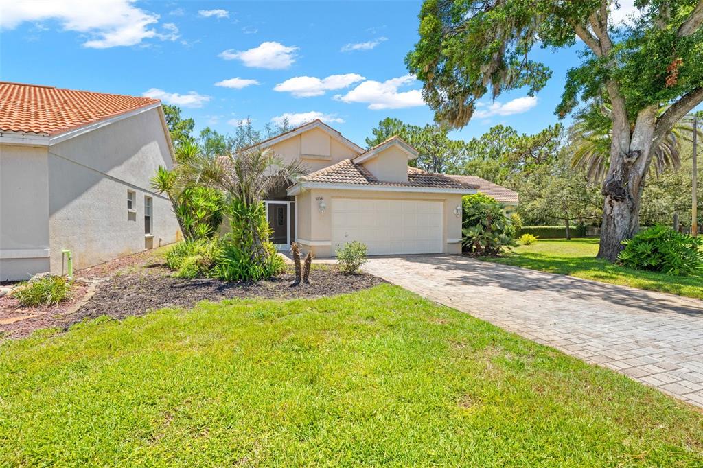 A single-story house with a tiled roof, a paved driveway, and a large front yard — 9354 MISSISSIPPI RUN, WEEKI WACHEE, FL