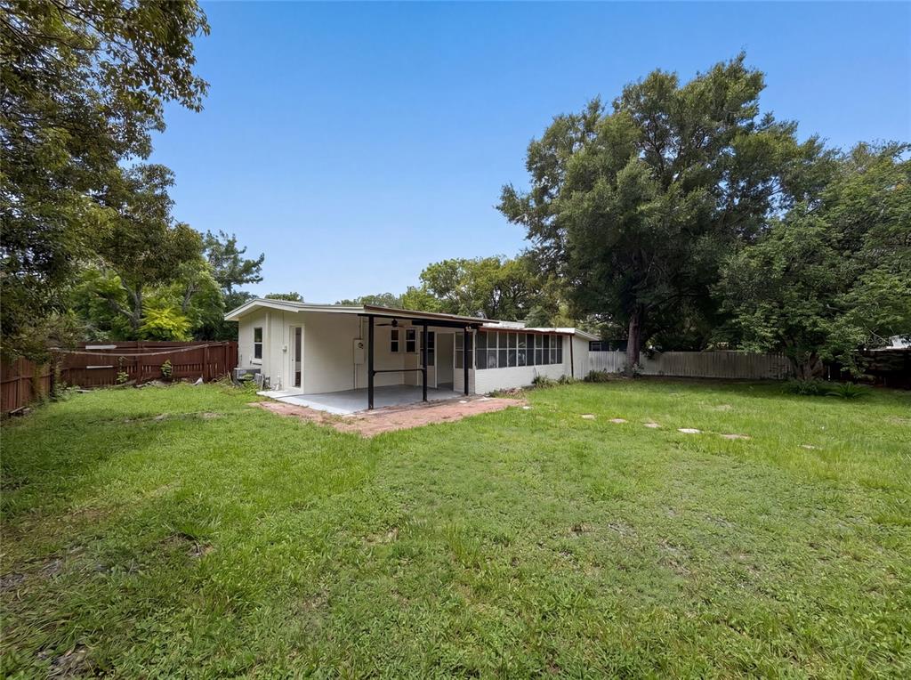 A backyard view of a house with a covered patio and an attached screened-in porch — 1502 DAROCA DRIVE, DELTONA, FL
