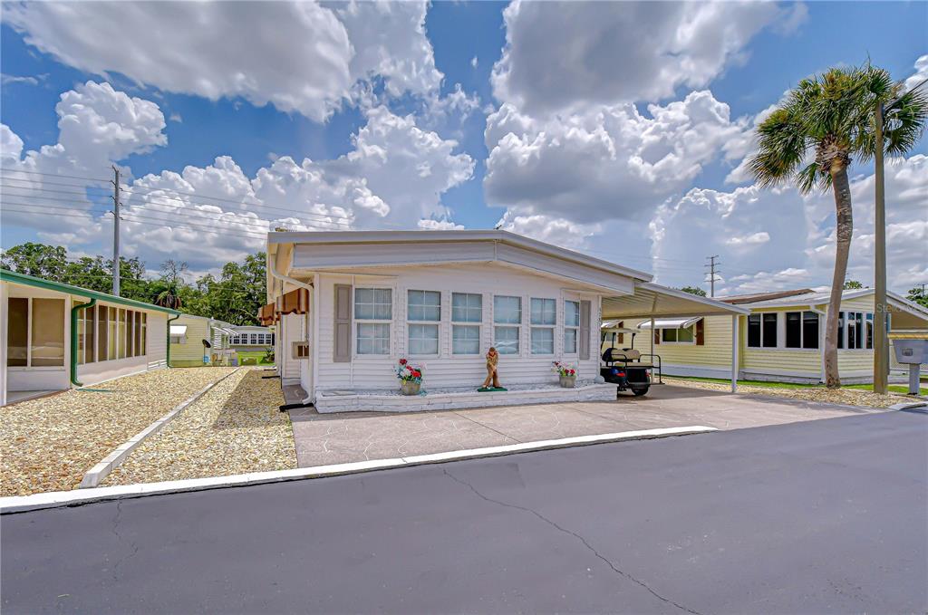 A white manufactured home with a carport, concrete driveway, and a palm tree — 37816 BARCELONA AVENUE, ZEPHYRHILLS, FL