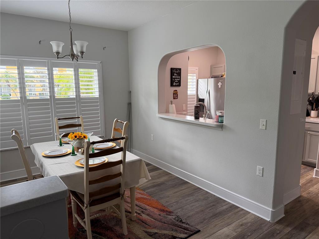 A dining area features a table with chairs, a pass-through window to the kitchen, and shutters — 20705 MOUNTAIN WHISTLER AVENUE, VENICE, FL