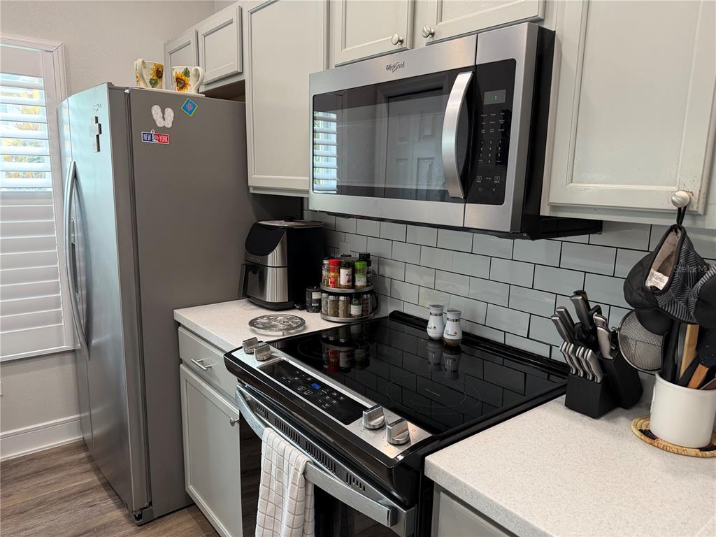 A kitchen features light gray cabinets, stainless steel appliances, and a white subway tile backsplash — 20705 MOUNTAIN WHISTLER AVENUE, VENICE, FL