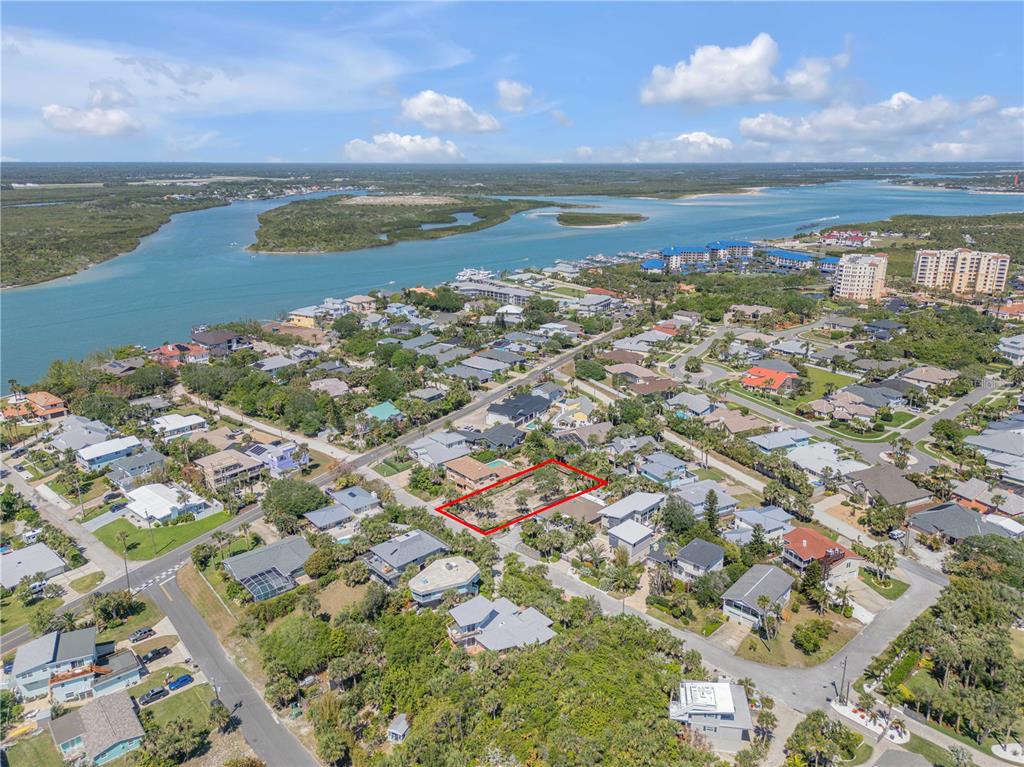 An aerial view shows a vacant, rectangular residential lot outlined in red within a coastal neighborhood — 204 DUNE CIRCLE, NEW SMYRNA BEACH, FL