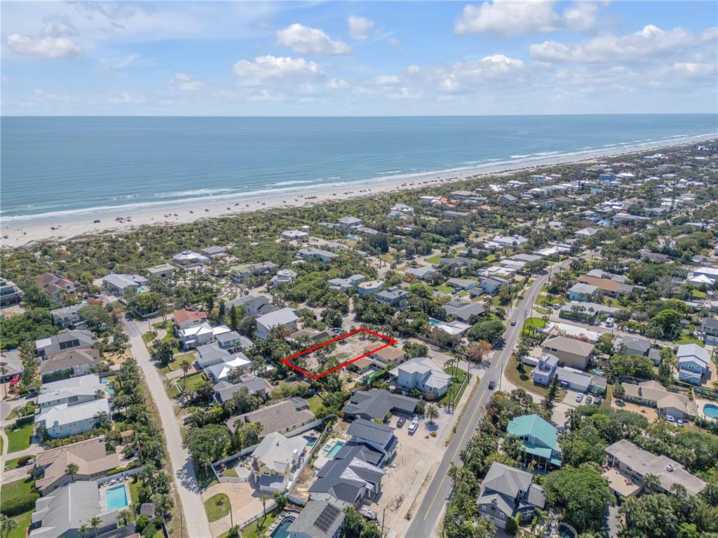 An aerial view shows a vacant residential lot outlined in red near a sandy beach — 204 DUNE CIRCLE, NEW SMYRNA BEACH, FL