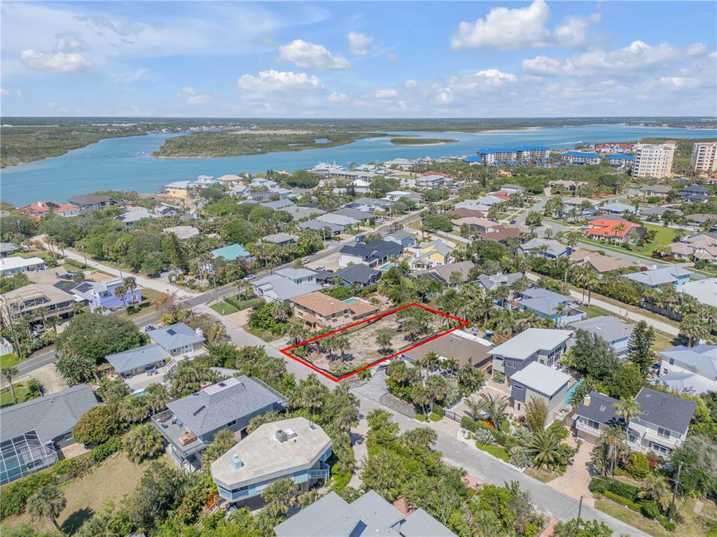 An aerial view shows a vacant, rectangular residential lot outlined in red within a coastal neighborhood — 204 DUNE CIRCLE, NEW SMYRNA BEACH, FL
