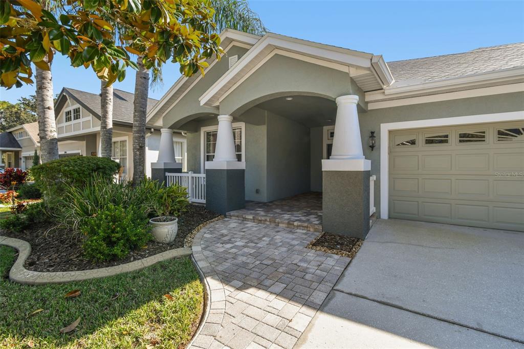 A single-story house exterior features a paved walkway, covered entryway with columns, and attached garage — 21753 GARDEN WALK LOOP, LAND O LAKES, FL