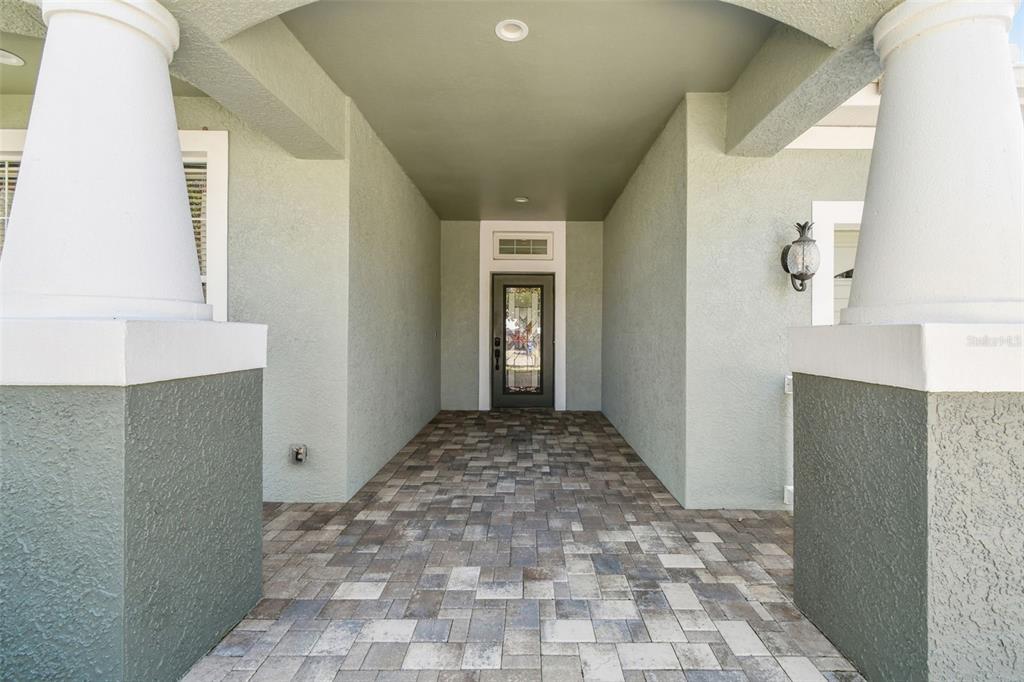A covered entryway features a paver floor, two large white columns, and a glass-paneled door — 21753 GARDEN WALK LOOP, LAND O LAKES, FL