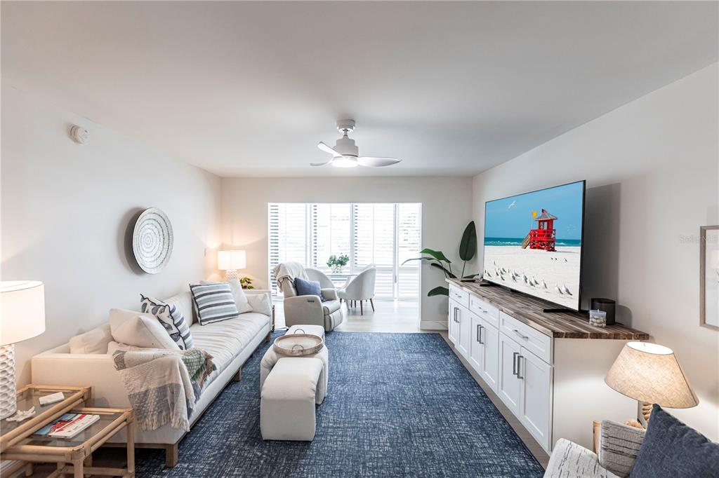 A living room features a white sofa, blue area rug, and a television on a console — 1055 W PEPPERTREE DRIVE UNIT 106AA, SARASOTA, FL