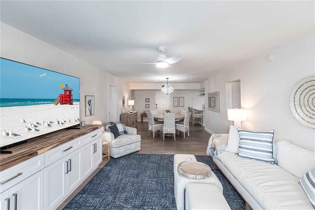 A living room and dining area feature white furniture, a blue rug, and beach decor — 1055 W PEPPERTREE DRIVE UNIT 106AA, SARASOTA, FL