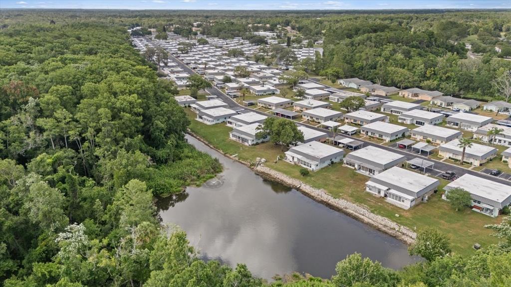 An aerial view shows a residential community with rows of houses beside a small pond — 11635 BAYONET LANE UNIT B, NEW PORT RICHEY, FL