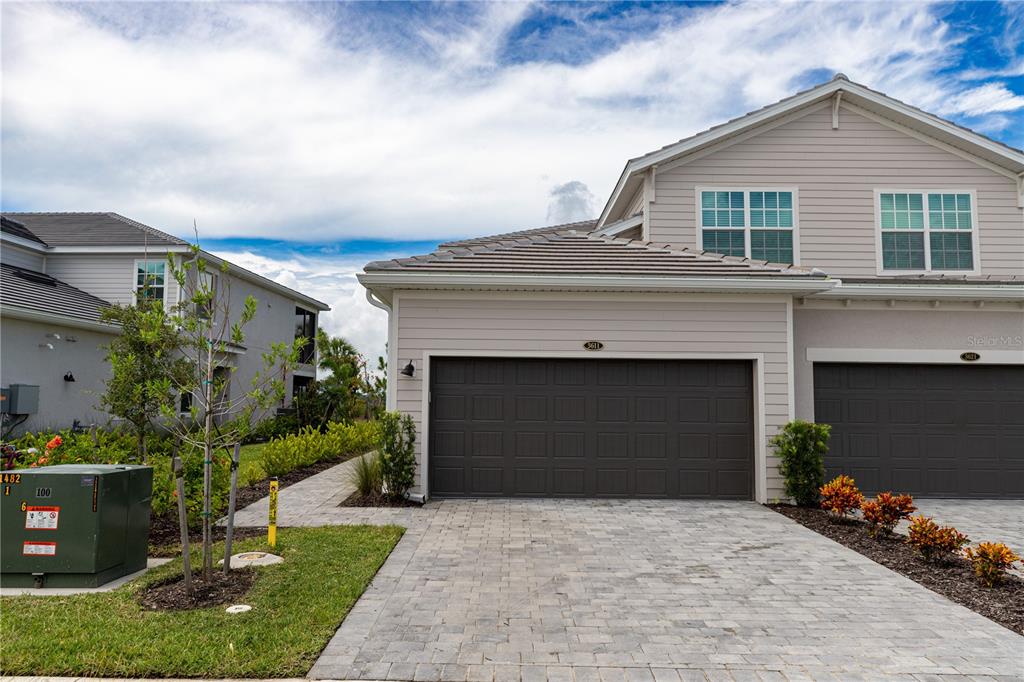 A two-story townhouse features a dark brown garage door and a paved driveway — 16572 KINGWOOD LANE UNIT 3611, PUNTA GORDA, FL