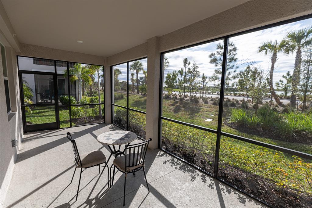 A screened-in patio features a small bistro table and chairs overlooking a landscaped yard — 16572 KINGWOOD LANE UNIT 3611, PUNTA GORDA, FL