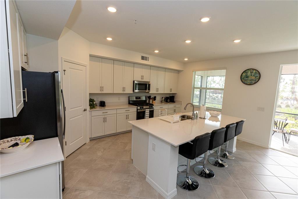 A kitchen features white cabinetry, a central island with bar seating, and tile flooring — 16572 KINGWOOD LANE UNIT 3611, PUNTA GORDA, FL