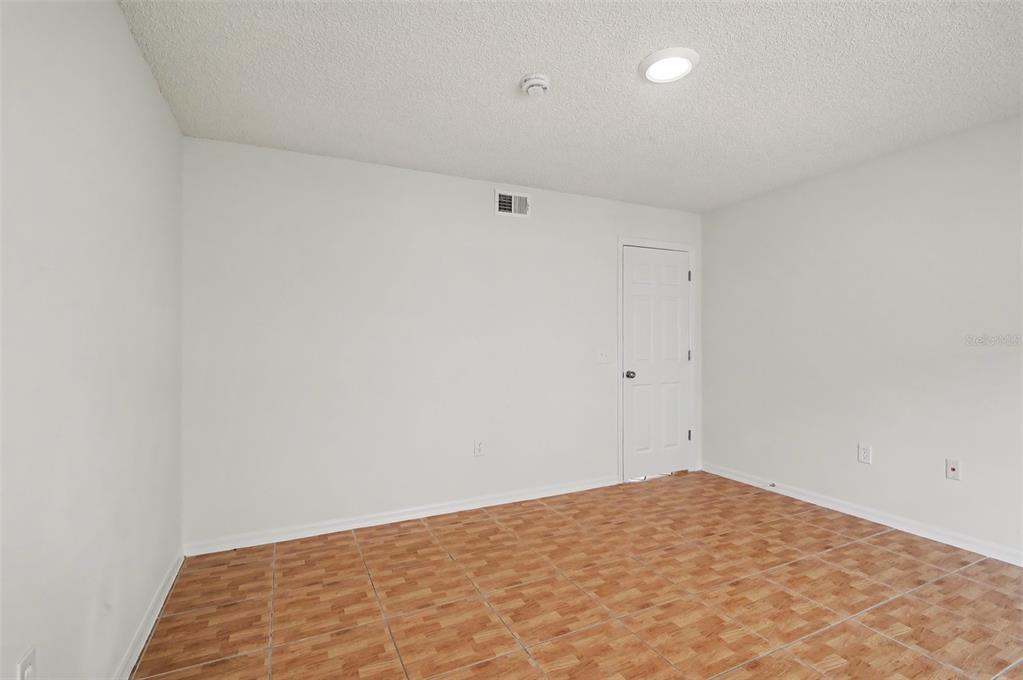 An empty room with white walls, a textured ceiling, and brown wood-look tile flooring — 1093 AMANDA KAY CIRCLE, SANFORD, FL