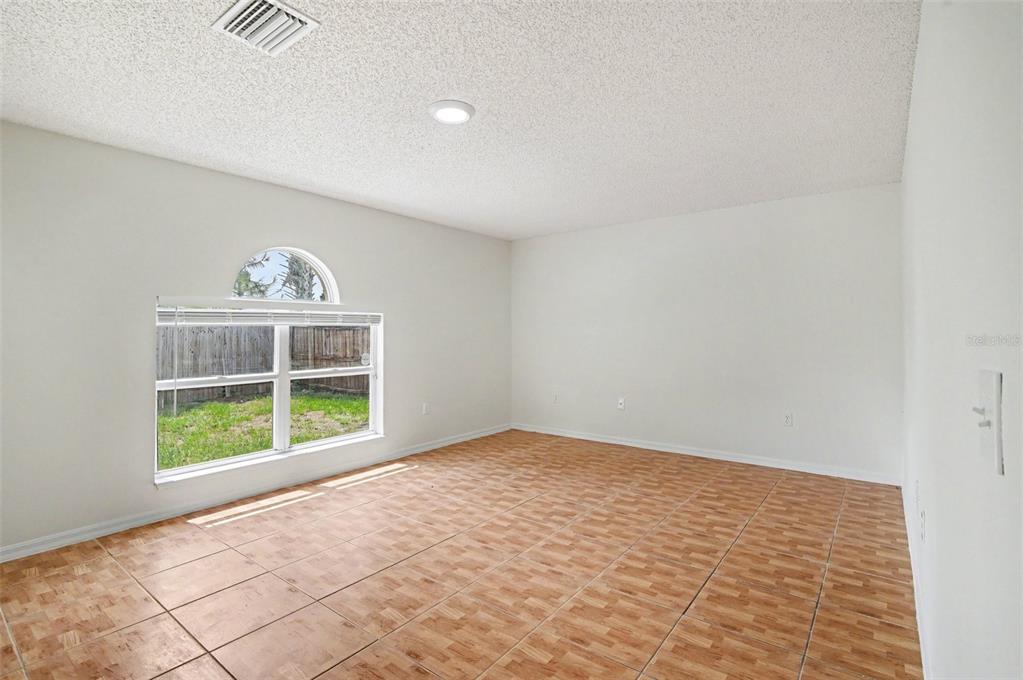 An empty room with light-colored walls, a large window, and brown wood-look tile flooring — 1093 AMANDA KAY CIRCLE, SANFORD, FL