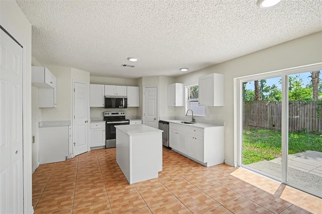 A kitchen with white cabinets, a center island, tile flooring, and a sliding glass door — 1093 AMANDA KAY CIRCLE, SANFORD, FL