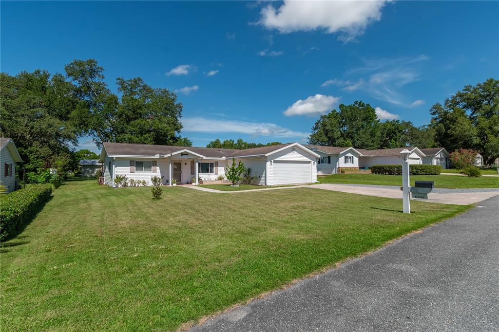 A single-story white house with a garage and a front lawn under a blue sky — 6444 SW 61ST COURT, OCALA, FL