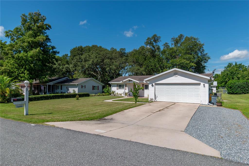 A white single-story house with a two-car garage sits on a large grassy lawn — 6444 SW 61ST COURT, OCALA, FL
