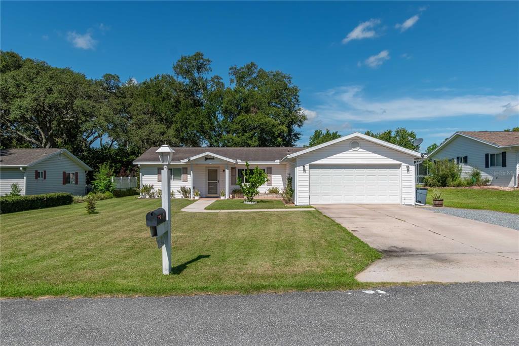 A single-story house with a white garage and a large front lawn under a blue sky — 6444 SW 61ST COURT, OCALA, FL