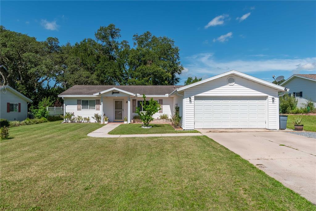 A single-story white house with a front-facing garage and a grassy lawn — 6444 SW 61ST COURT, OCALA, FL