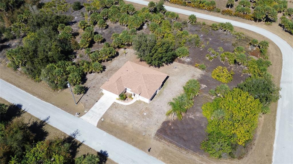 An aerial view shows a single-story house with a brown roof on a wooded lot — 13460 CEDAR CITY AVENUE, PORT CHARLOTTE, FL