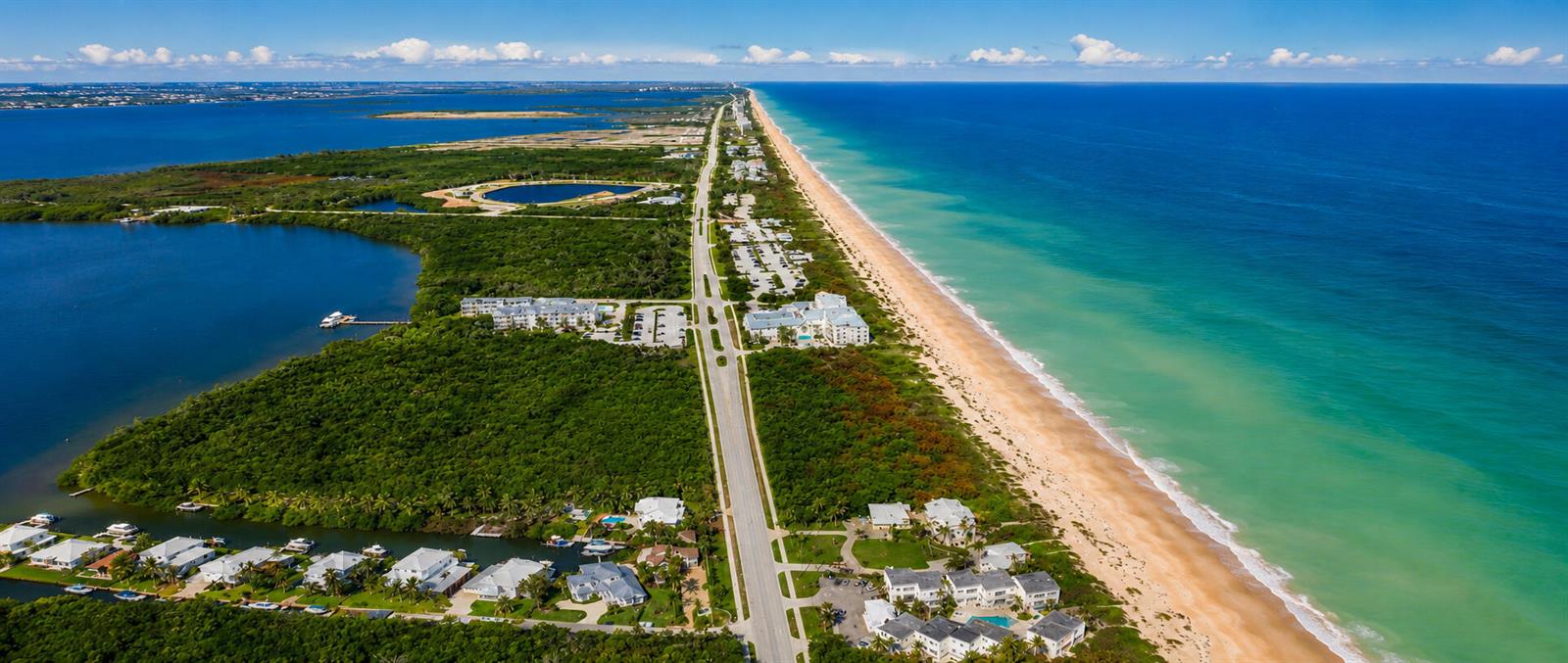 An aerial view shows a coastal road separating a lush green landscape from the ocean — 3541 NE Ocean Boulevard NE # 15, Jensen Beach FL 34957, JENSEN BEACH, FL