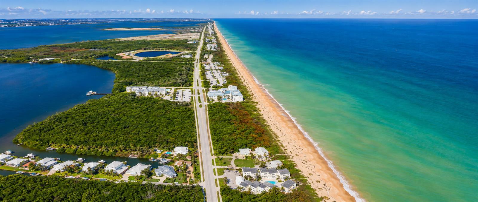 An aerial view shows a coastal road separating a dense forest from a sandy beach — 3541 NE Ocean Boulevard NE # 15, Jensen Beach FL 34957, JENSEN BEACH, FL