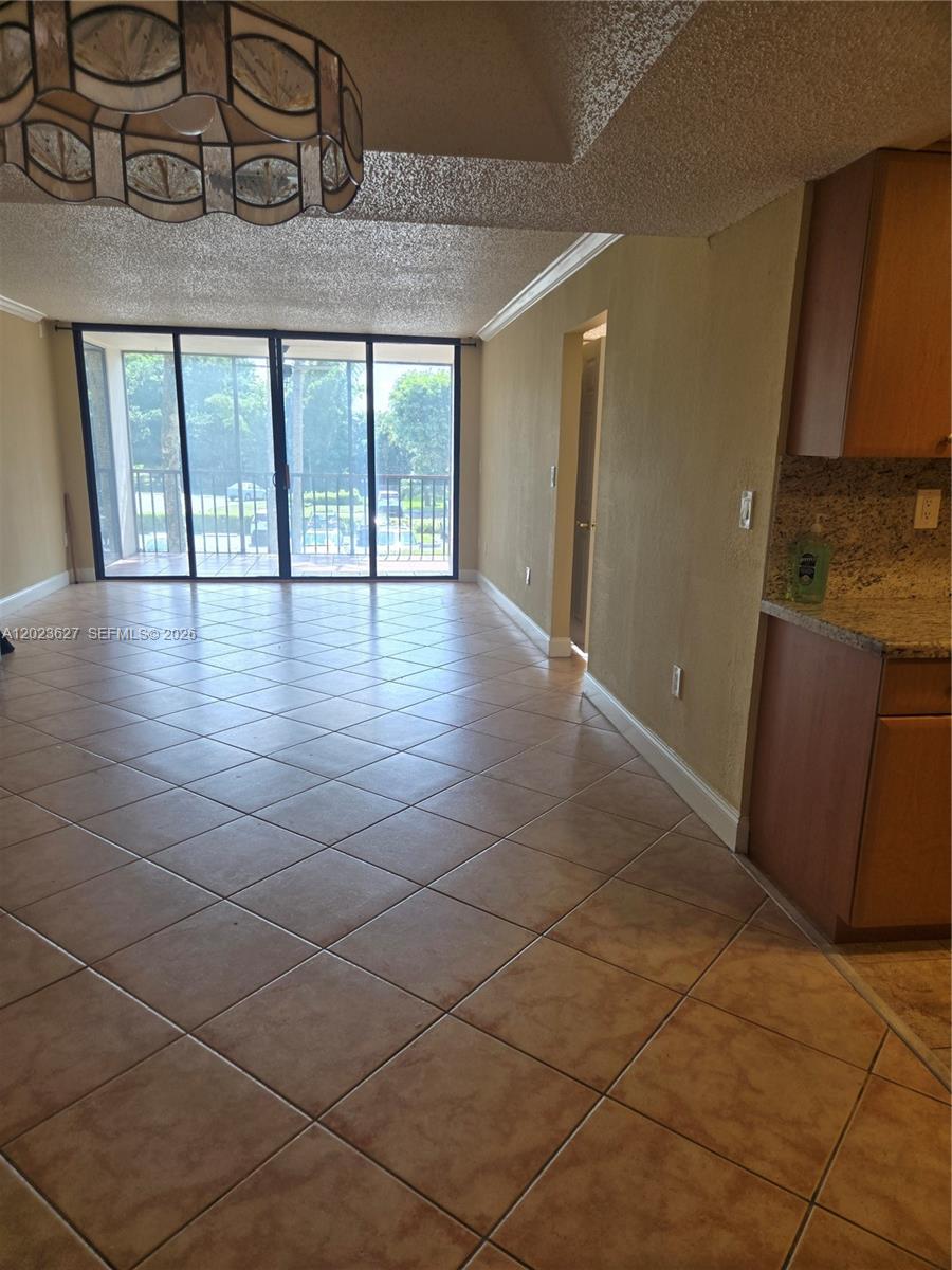 A tiled dining area features a decorative chandelier and sliding glass doors leading to a balcony — 9735 NW 52nd St # 208, Doral FL 33178, DORAL, FL