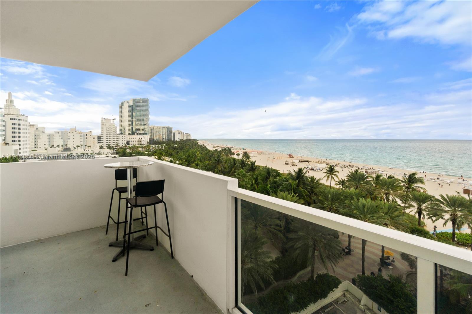 A balcony with a small table and two chairs overlooks a beach and ocean — 100 Lincoln Rd # 847, Miami Beach FL 33139, MIAMI BEACH, FL