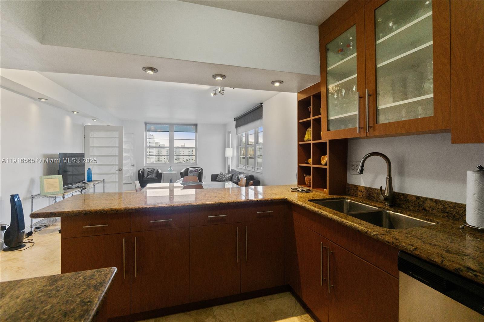 A kitchen with wood cabinets and granite countertops overlooks an open-concept living area — 100 Lincoln Rd # 847, Miami Beach FL 33139, MIAMI BEACH, FL
