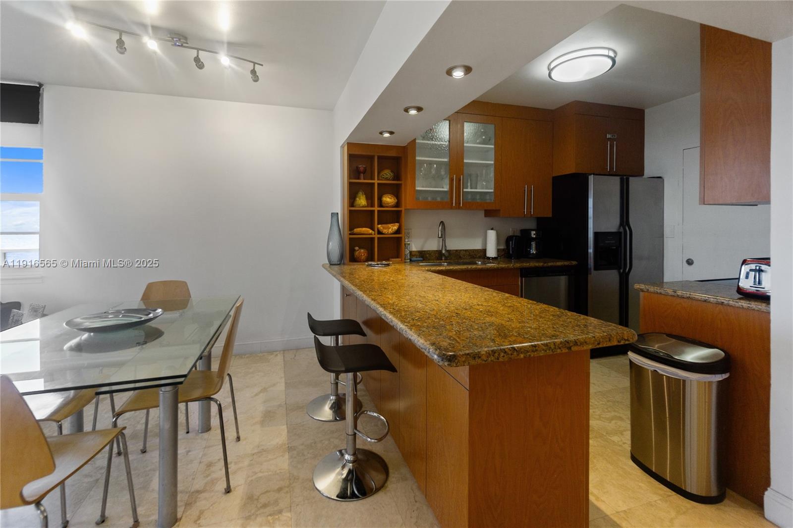A kitchen features wood cabinets, granite countertops, a breakfast bar, and an adjacent dining area — 100 Lincoln Rd # 847, Miami Beach FL 33139, MIAMI BEACH, FL