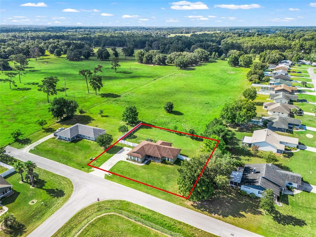 An aerial view shows a single-story house with a brown roof on a grassy lot — 7474 SE 107 PLACE, BELLEVIEW, FL