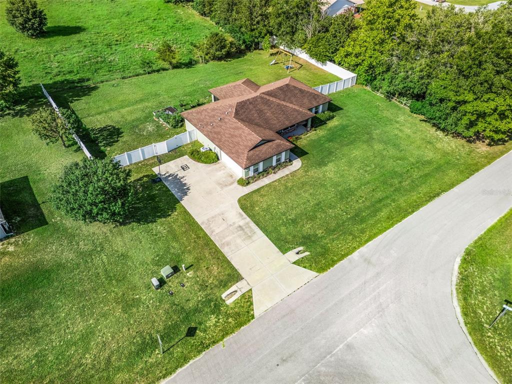 An aerial view shows a single-story house with a brown roof, driveway, and fenced yard — 7474 SE 107 PLACE, BELLEVIEW, FL