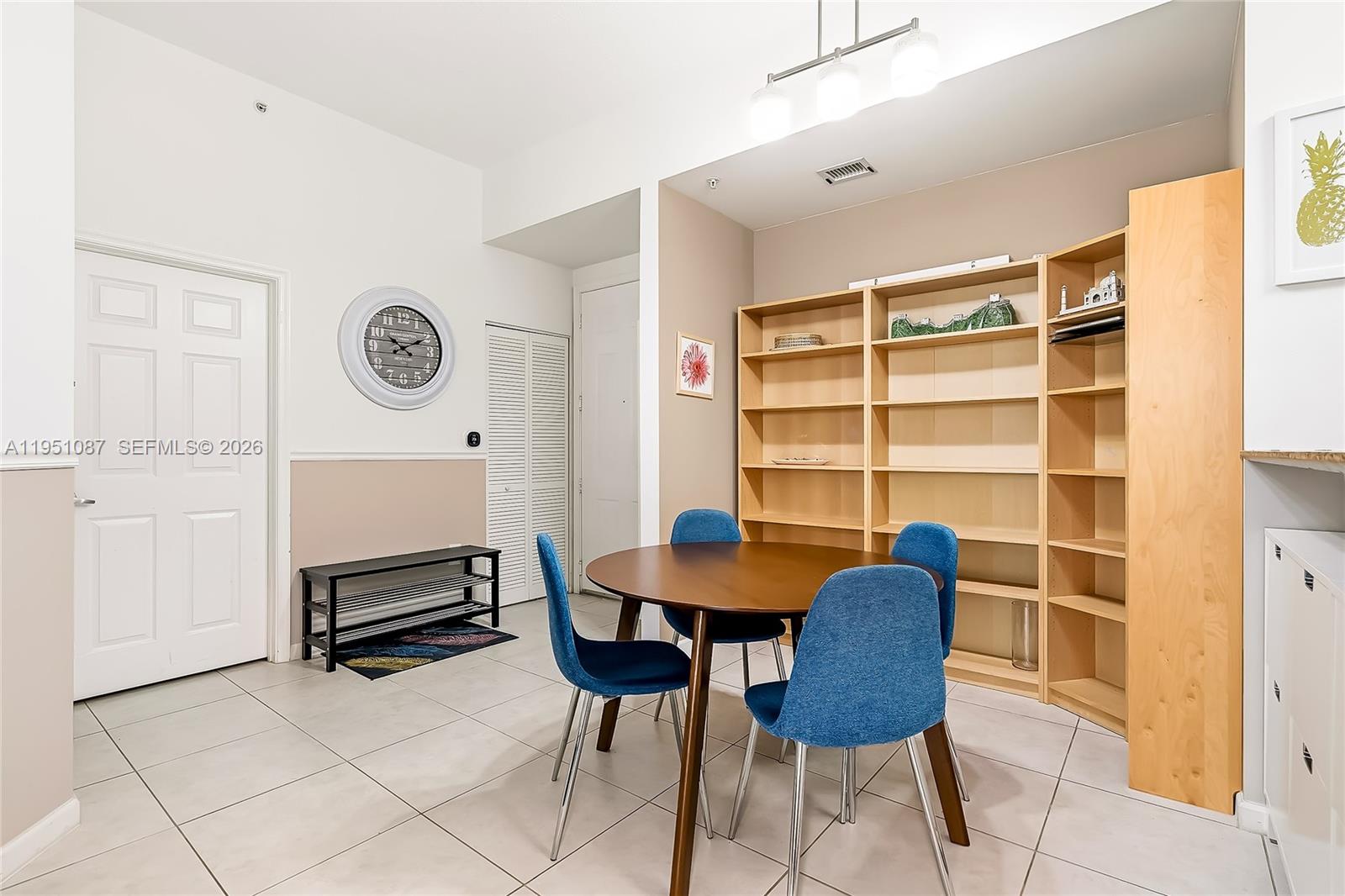 A dining area features a round wooden table, four blue chairs, and built-in shelving — 2080 S Ocean Dr # 103, Hallandale Beach FL 33009, HALLANDALE BEACH, FL